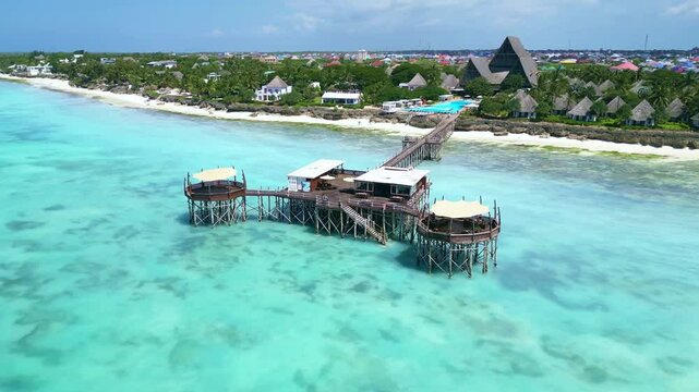Aerial views of Zanzibar coastline, drone Tanzania 4k. Bungalows hut on pier dock in ocean. Tropical island vacation. Famous tourism destination in Africa. 