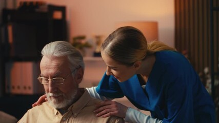Female nurse talking with aged man who's reading a book in a nursing home, care