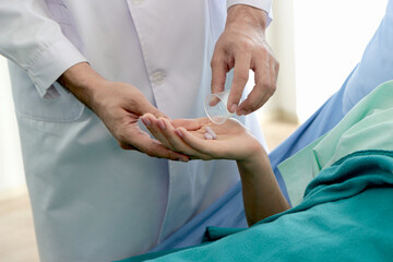 Doctor hand giving medicine to patient who laying in bed at the hospital, ill woman hold  pills on hand, helping sick female taking medicine on the bed