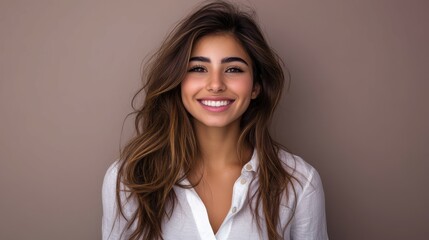Obraz premium Smiling young woman in a white shirt against a neutral background