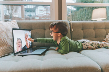 A little boy face timing with his grandparents at home. 