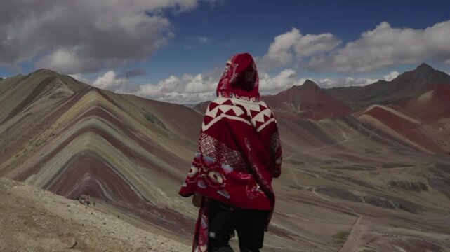 Tourist man with red peruvian poncho explores Rainbow mountain Per&uacute;. Seven colors Cusco Peru