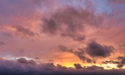 Fototapeta premium A beautiful sky tinted by the sun leaving vibrant shades of gold, pink, blue and multicolored. Clouds in the twilight evening and morning sky. Cloudy sky background in the evening, and during the day.