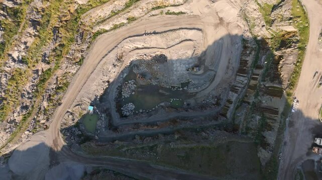 High Drone footage approaching Les Vardes Quarry Guernsey showing quarry, equipment and surrounding area on bright sunny day
