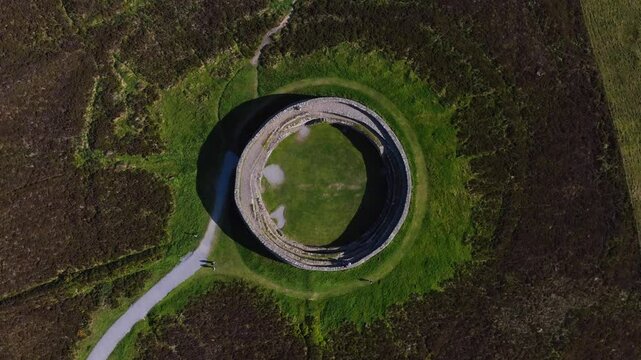 Grianan of Aileach, County Donegal, Ireland, June 2023. Drone Bird's Eye view counter clockwise descent above the stone hillfort at Inishowen with people exploring the iconic national monument.