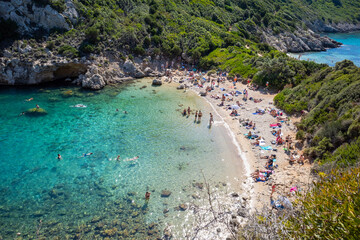 A beach with a large crowd of people and a clear blue ocean