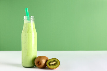 Bottle of fresh kiwi smoothie on white table