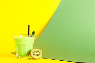 Glass of fresh kiwi smoothie with mint on colorful background
