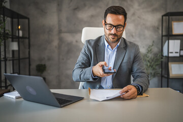 Obraz premium Businessman sit in office and have contactless payment on cellphone