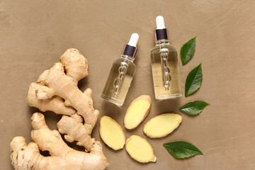 Bottles of ginger cosmetic oil and leaves on brown background