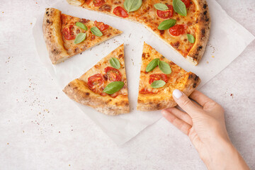 Woman taking piece of tasty pizza Margarita with tomatoes and basil on white table