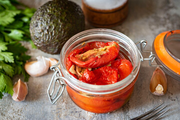 Dried tomatoes in a glass jar on a gray background. Close-up.