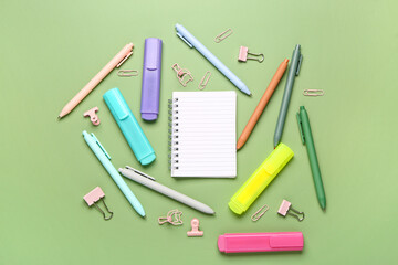 Blank notebook with school stationery on green background