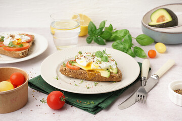 Plates of tasty sandwiches with egg on light background