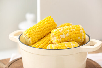 Cooking pot with boiled corn cobs on white background, closeup