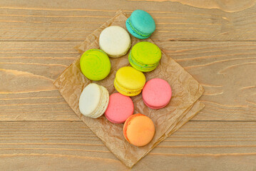 Baking paper with sweet macaroons on wooden table