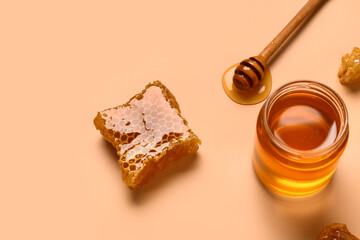 Jar with sweet honey and combs on orange background