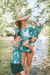 A mother and children at the river in summer wearing matching bathing suits. 