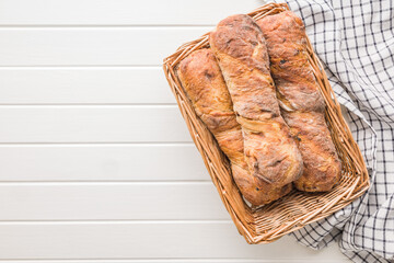 Crusty rustic baguette in basket on white table. Top view.