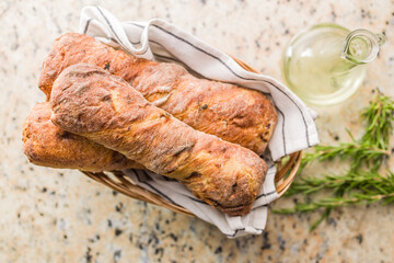 Crusty rustic baguette in basket on kitchen table. Top view.