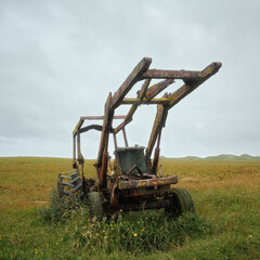 Old style farm tractor sitting on a green grass field. Isle of North Uist, Scotland