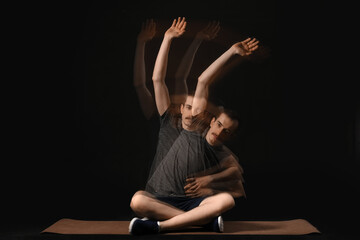 Young male fitness trainer exercising on yoga mat in motion against black background