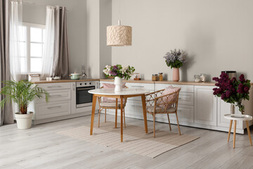 Vases with beautiful lilac flowers in kitchen