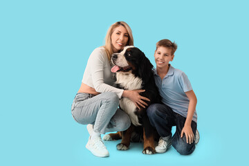 Little boy and his mother with Bernese mountain dog on blue background