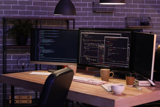 Programmer's workplace with computer monitors in office at night