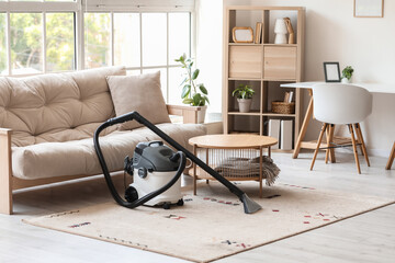 Modern vacuum cleaner on carpet in light living room