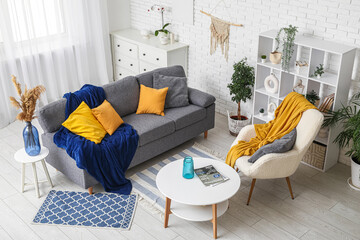 Interior of light living room with soft couch, armchair and coffee table