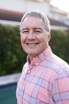Smiling senior man in plaid shirt enjoying outdoor time with diverse friends, at home
