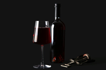 Bottle, glass of red wine and opener on black background