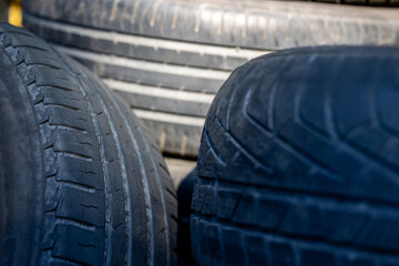 Obraz premium Worn and damaged tread of old tires lying in a landfill. Decreased road safety and environmental pollution from rubber waste