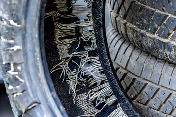 An old blown out car tire in a used tire landfill. Old tires polluting the environment
