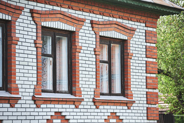Part of a red and white brick wall with classical wooden windows. Part of a traditional brick house with decoration