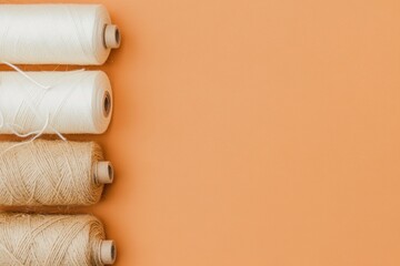 Obraz premium Four spools of thread in neutral colors on an orange background
