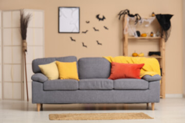 Interior of modern living room decorated for Halloween with sofa, shelving unit and folding screen