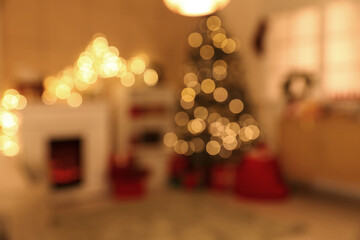 Interior of cozy living room with fireplace, shelving unit and glowing Christmas tree decorated for holiday at night, blurred view