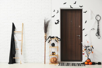 Wooden door and Halloween decorations with paper bats, broom and fetters in interior of hallway