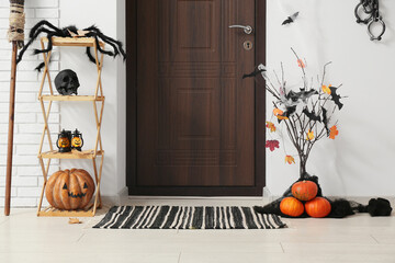 Wooden door and Halloween decorations with paper bats, broom and fetters in interior of hallway