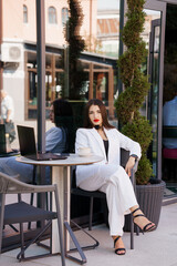 Elegant Business Woman in Striped Suit Relaxing at a Chic Outdoor Café