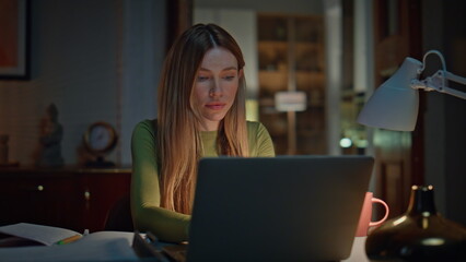 Online student studying late evening looking laptop. Woman freelancer working