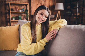 Obraz premium Photo portrait of attractive teen woman sit couch have rest dressed yellow outfit cozy day light home interior living room
