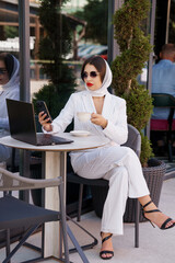 Elegant Business Woman Sipping Coffee with Laptop at Outdoor Café