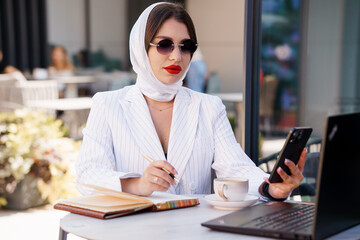 Elegant Business Woman Engaged in Work Outdoors with Laptop and Notebook