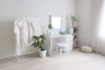 Blurred view of makeup room with table, clothes rack and shelf unit