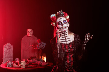 Fototapeta premium Portrait of woman in telephone call during Day of the Dead Mexican celebration honoring dead loved ones. Person talking on cellphone while doing ancient Aztec custom of celebrating ancestors