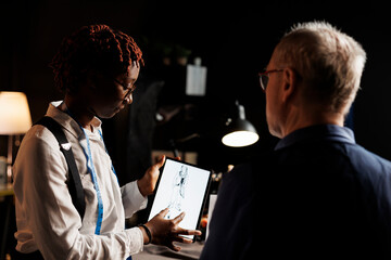 Creative fashion designers working on trendy baggy fashionable outfit in atelier shop workspace. Apprentice couturier and elderly master checking sartorial collection sketch drawing