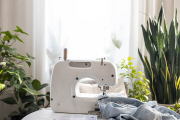 Workplace with a sewing machine. There are old blue jeans on the table.